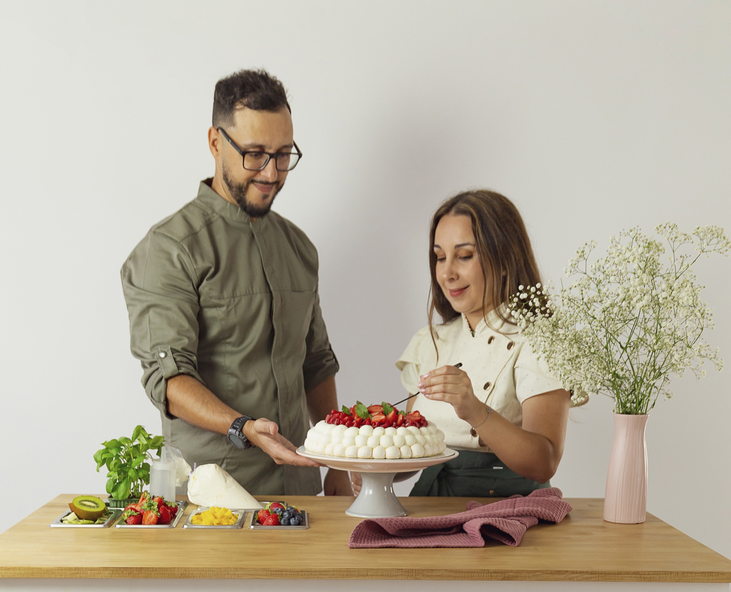 Duas pessoas a decorar um bolo na cozinha